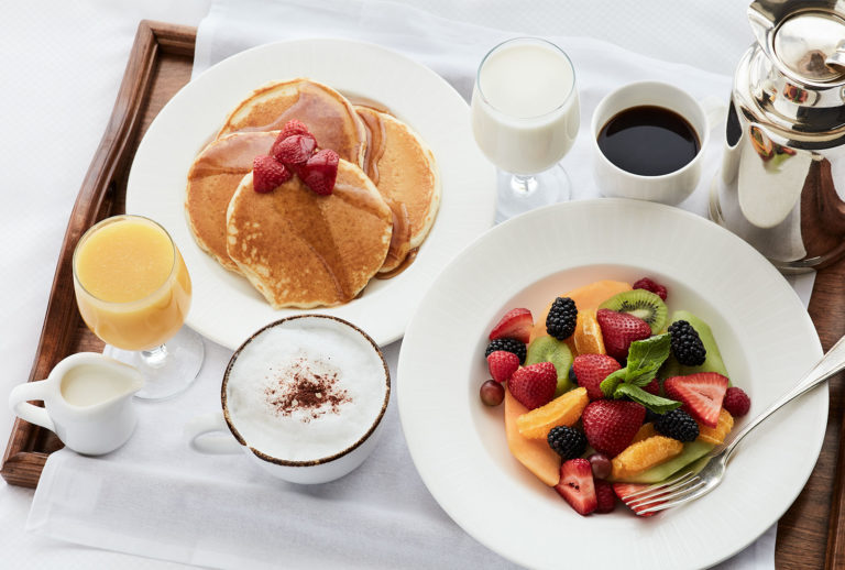 In-room dining order of pancakes, orange juice, coffee, cappuccino, and fresh fruit served on a tray