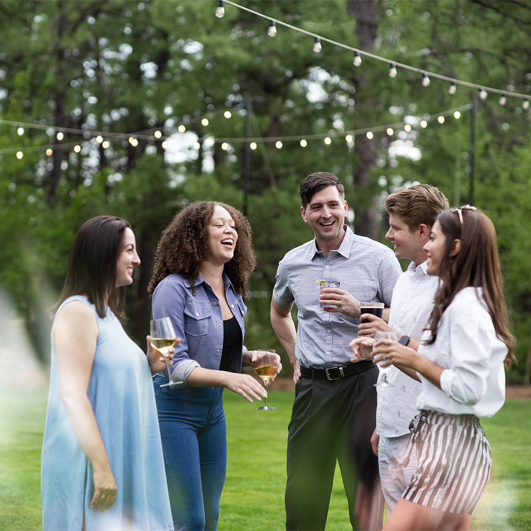 Group of friends standing in a circle with drinks in hand.