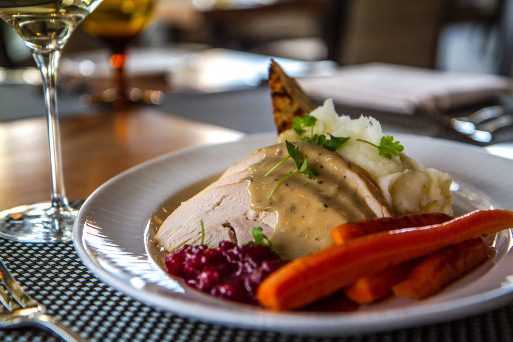 A plate full of sliced turkey with gravy, carrots and cranberry sauce.